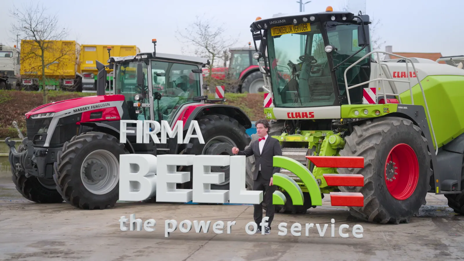 Beeld uit de teaser: de presentator tussen de machines, bij de metershoge letters 'FIRMA BEEL — the power of service'.